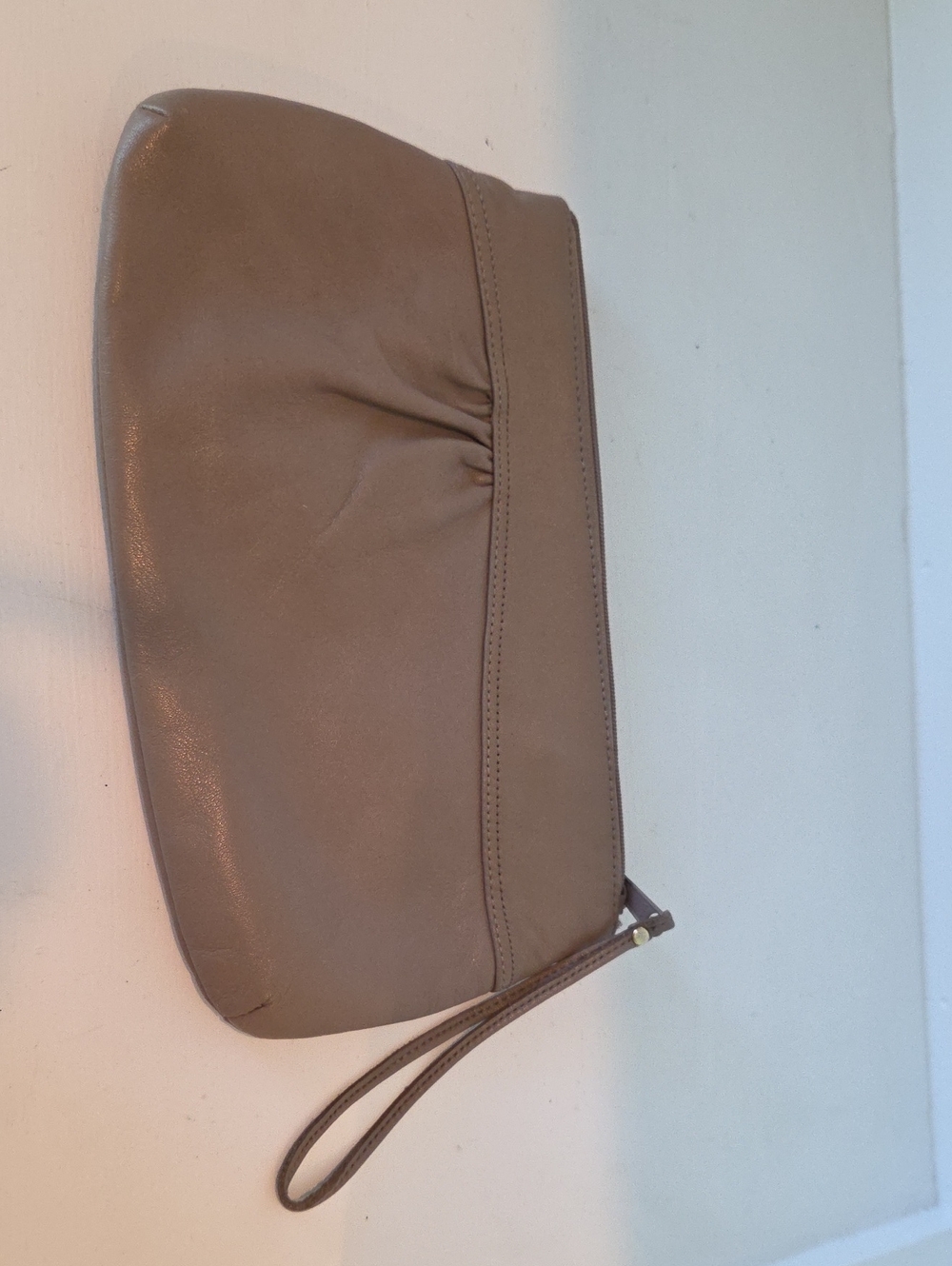 Taupe leather vintage clutch features a pleated front detail.